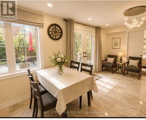 A dining room with a table set for four and a chandelier hanging from the ceiling.