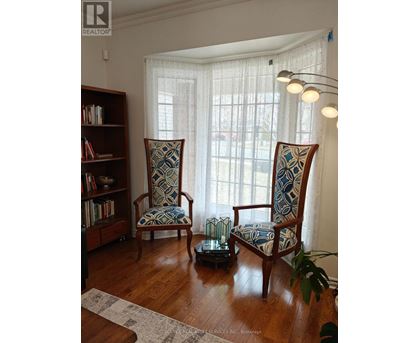 Two chairs with blue and white patterned cushions are in front of a window with white curtains.