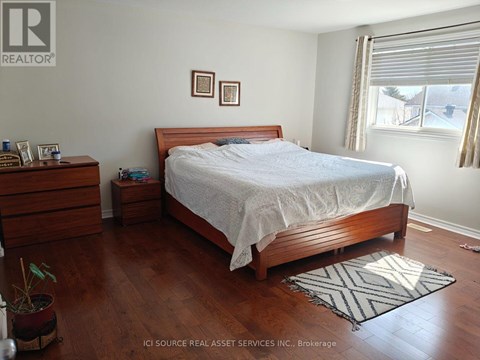 A bedroom with a bed, nightstand, and a plant.