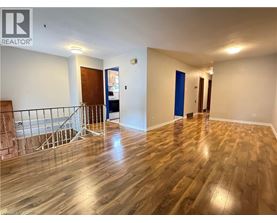A room with wooden flooring and a staircase with a metal railing.