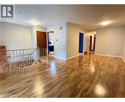 A room with wooden flooring and a staircase with a metal railing.