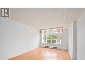 A white room with a window and wooden flooring.