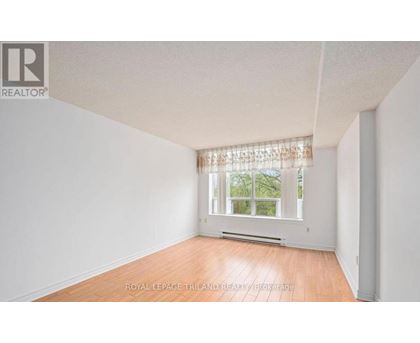 A white room with a window and wooden flooring.