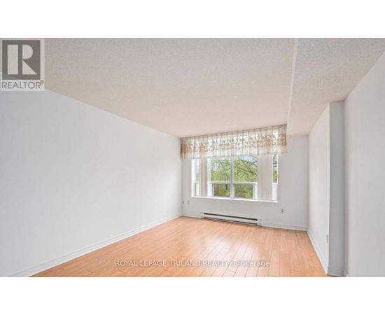 A white room with a window and wooden flooring.