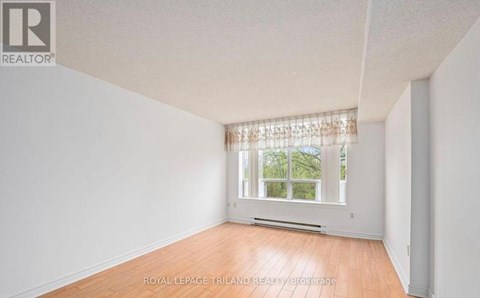 A white room with a window and wooden flooring.