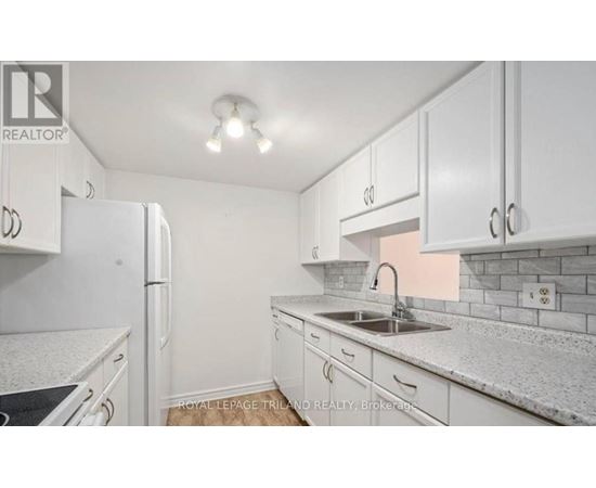 A white kitchen with a sink and a refrigerator.