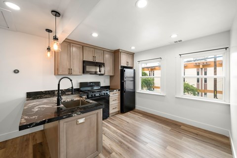 A modern kitchen with wooden cabinets and black countertops.