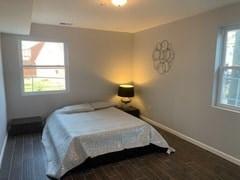 A bedroom with a bed, lamp, and window.