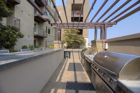 A long stainless steel grill is on the right side of a patio.