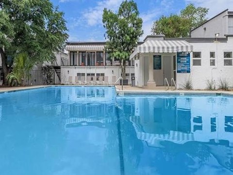 A swimming pool in front of a building with a white exterior and a blue signboard.