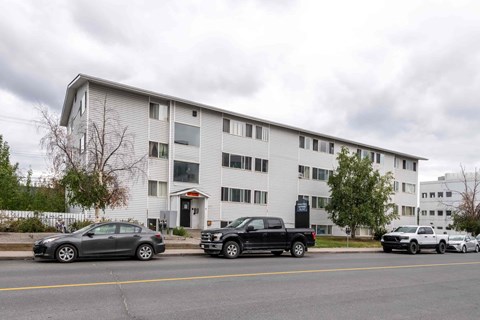 A grey building with cars parked in front.