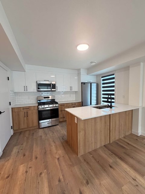 A modern kitchen with wooden floors and white cabinets.