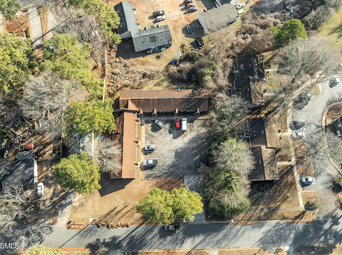 A bird's eye view of a parking lot with cars and a building.