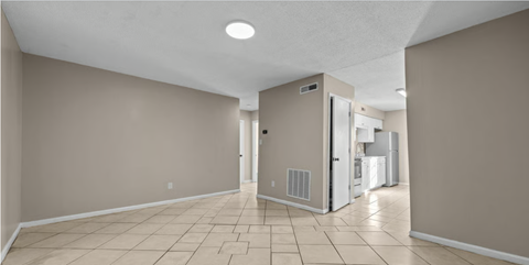 A spacious room with beige walls and a tiled floor.