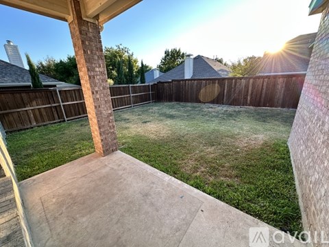 A backyard with a wooden fence and a concrete patio.