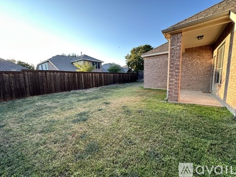 A backyard with a wooden fence and a house.