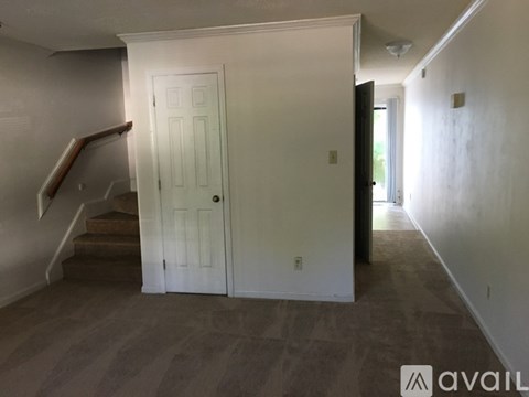 A room with a white door and a staircase with a wooden handrail.