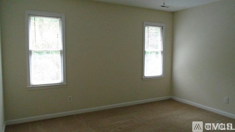 A room with two windows and beige walls.