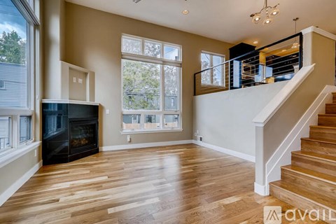 A spacious living room with wood flooring and a staircase leading to the upper level.