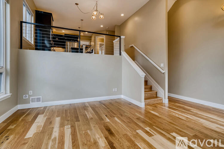 A spacious room with wooden flooring and a staircase leading to the upper level.