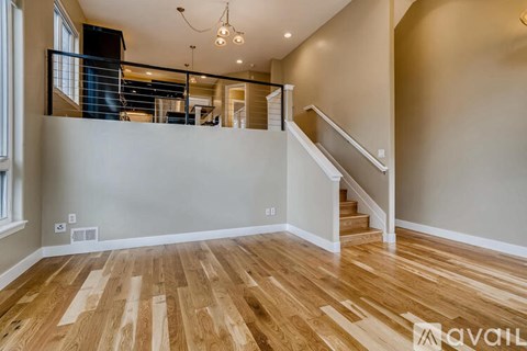 A spacious room with wooden flooring and a staircase leading to the upper level.