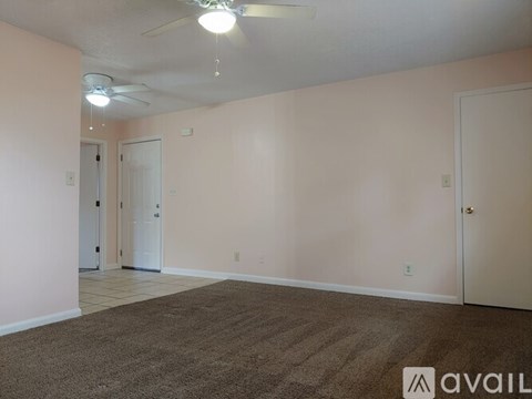 A room with a carpeted floor and a ceiling fan.