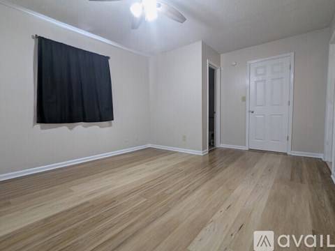 A room with a carpeted floor, a ceiling fan, and a window.