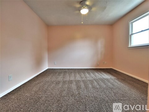 A room with a carpeted floor and a window on the wall.