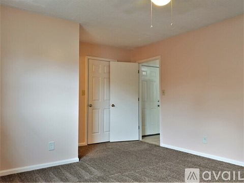 A room with a carpeted floor and two doors, one of which is open.