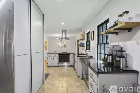 A modern kitchen with a refrigerator on the left and a sink on the right.