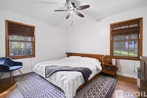 A bedroom with a bed, a chair, and a ceiling fan.