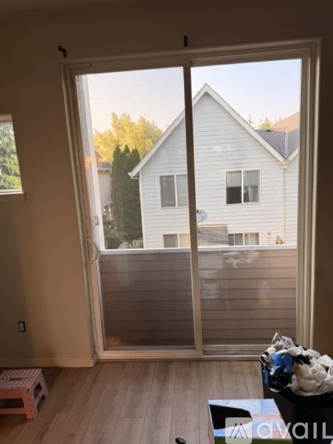 A sliding glass door opens to a backyard with a house and trees in the background.