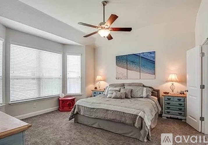 A bedroom with a bed, nightstands, and a ceiling fan.