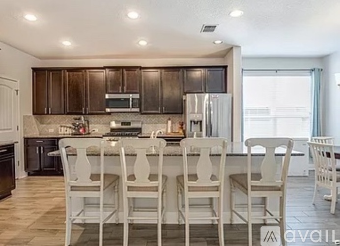 A kitchen with brown cabinets and white chairs.
