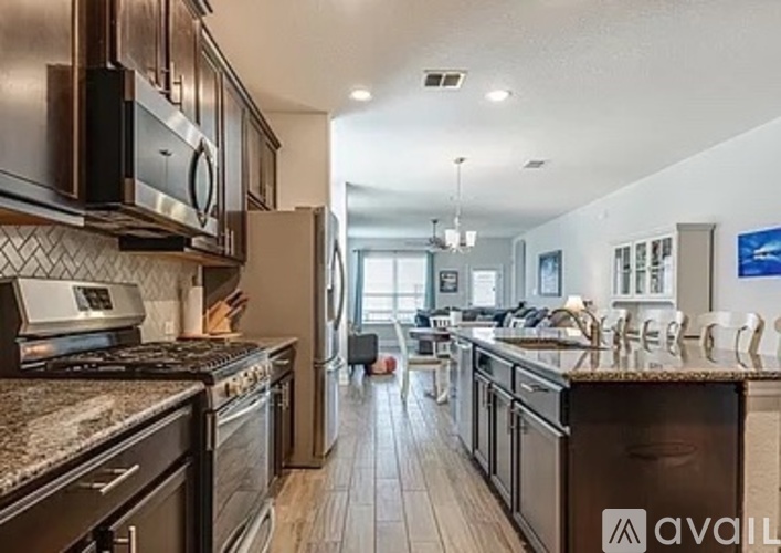 A modern kitchen with dark brown cabinets and stainless steel appliances.
