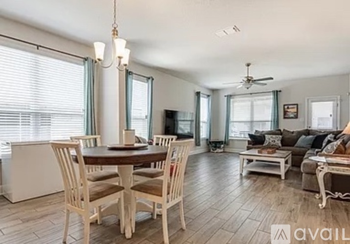 A dining room with a table set for four and a couch with a throw pillow.