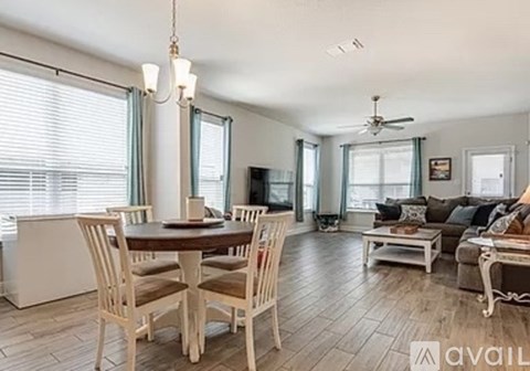 A dining room with a table set for four and a couch with a throw pillow.