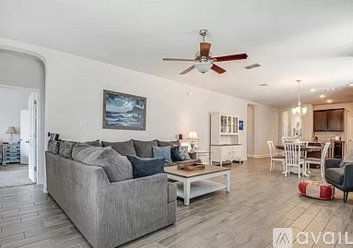 A living room with a grey couch and a ceiling fan.