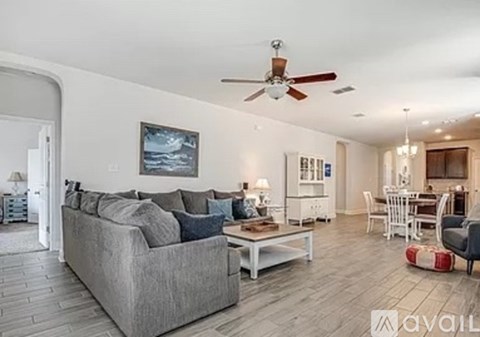 A living room with a grey couch and a ceiling fan.