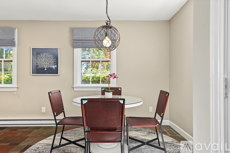 A dining room with a table, chairs and a hanging light fixture.