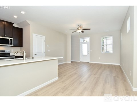 A spacious kitchen with wooden floors and a ceiling fan.