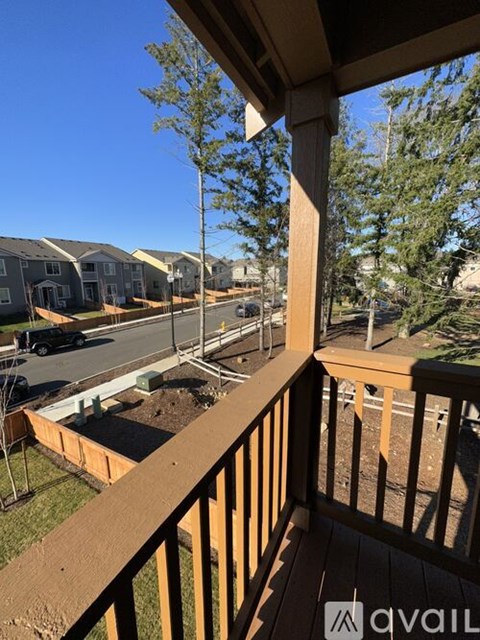 A wooden balcony overlooks a street with houses and trees.