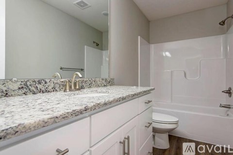 A bathroom with a marble countertop and white fixtures.
