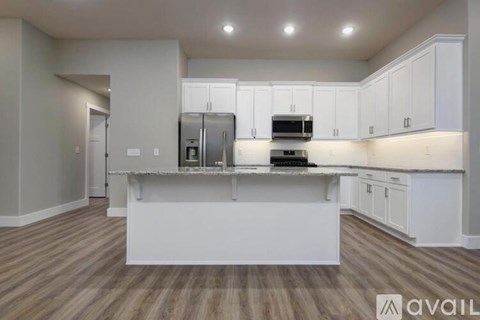A kitchen with white cabinets and a wooden floor.