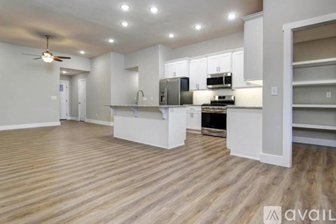 A spacious kitchen with white cabinets and a wooden floor.