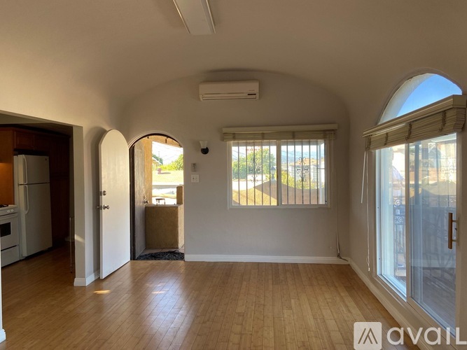 A spacious living room with wooden floors and arched doorways leading to other rooms.