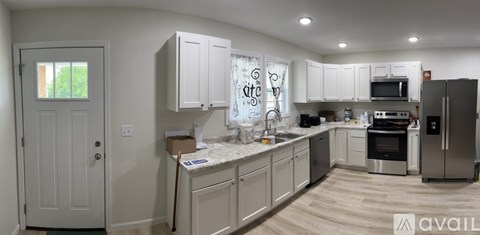A kitchen with white cabinets and a wooden floor.
