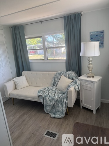A living room with a white couch and a lamp on a side table.