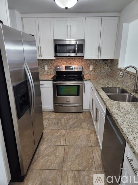 A kitchen with a stainless steel refrigerator, microwave, oven, and sink.