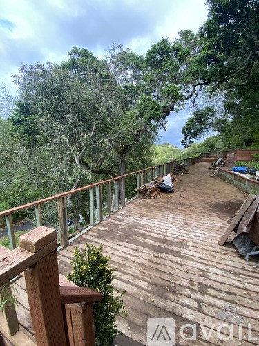 A wooden deck with a railing and a person sitting on it.